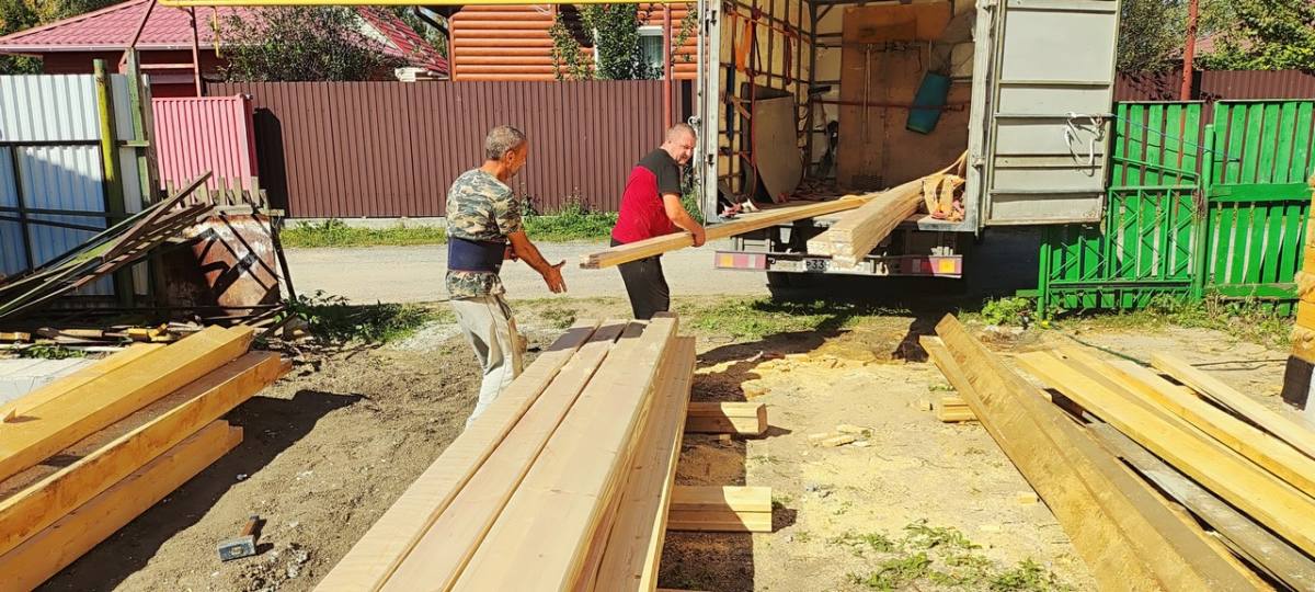 Двое рабочих несут пачку из кузова