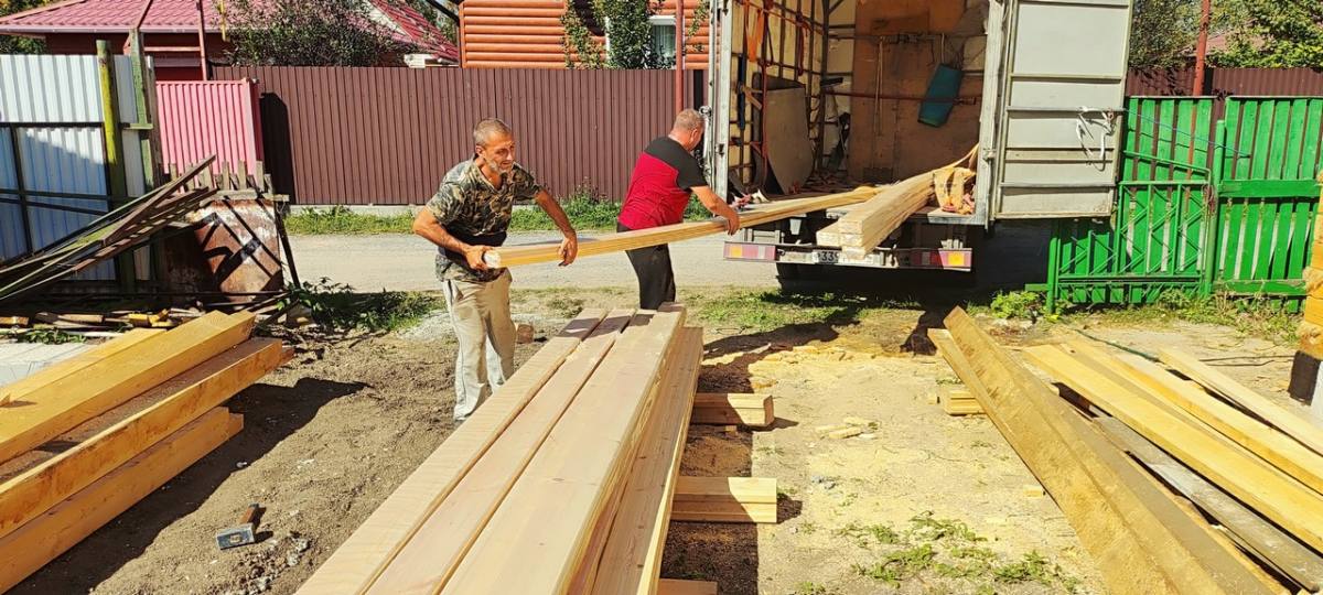 Рабочие вынимают пачку из кузова газели